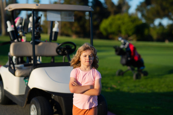 Kid in golf park near golf cart. Child summer vacation. Portrait of kid outdoors. Close-up face child playing outdoors in summer park - Foto, Imagem