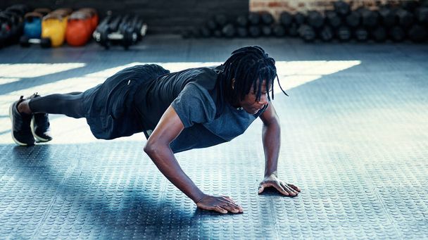 Concurreren met jezelf. een jonge man doet push-ups in een sportschool - Foto, afbeelding