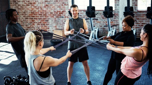 Finden Sie die Person, auf die Sie sich stützen können. eine Fitnessgruppe, die im Fitnessstudio mit Widerstandsbändern trainiert - Foto, Bild