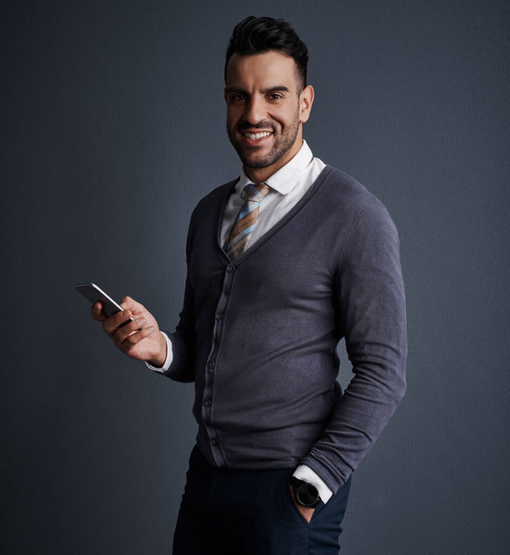 Dial my number and lets do business. Studio shot of a stylish young businessman using a mobile phone against a gray background - Φωτογραφία, εικόνα