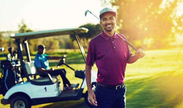 Ich will gewinnen. ein Golfer hält seinen Schläger mit einem Buggy im Hintergrund - Foto, Bild