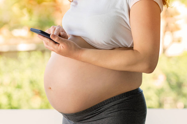 belly of a pregnant woman on a light natural background - Fotó, kép