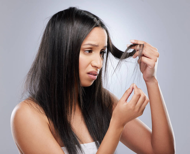 Hair problem, damage and woman in studio with worry for split ends, haircare crisis and weak tips. Beauty, salon and face of upset female person with frizz, dry texture and loss on gray background. - Photo, Image