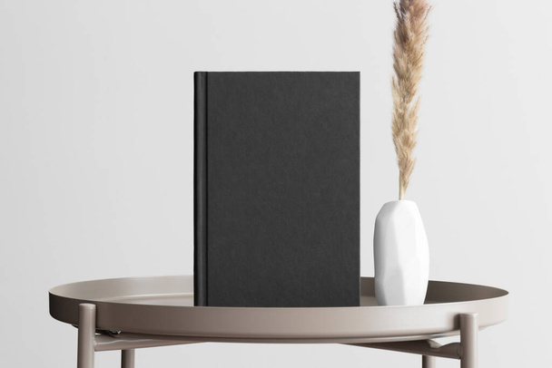 Black book mockup with a pampas decoration on the beige table. - Фото, зображення