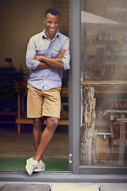 Laughing, coffee shop and man as small business owner at front door with arms crossed. Black entrepreneur person as barista, manager or funny waiter in restaurant for service, thinking and goals. - Foto, imagen