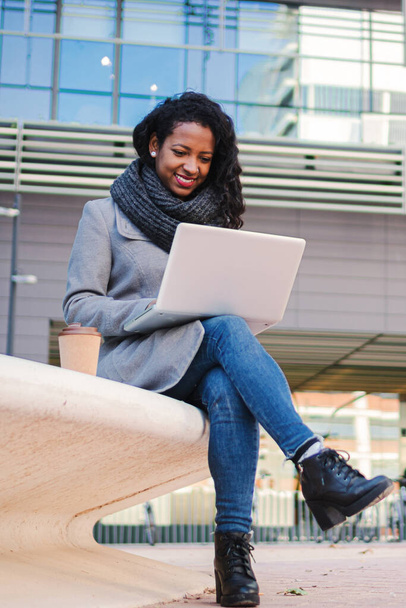Pionowy portret niesamowitej biznesowej młodej kobiety budzącej się z laptopem przed biurem. Przedsiębiorca freelance kobieta uśmiecha się i wpisując z notebooka, przeglądając w Internecie. Wysoka - Zdjęcie, obraz