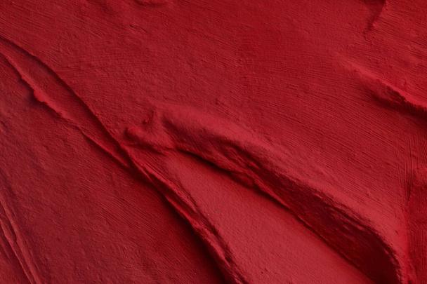 Decorative red putty background. Wall texture with filler paste applied with spatula, chaotic dashes and strokes over plaster. Creative design, stone pattern, cemen - Foto, afbeelding