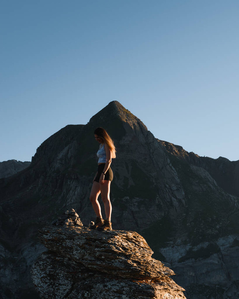 young girl having fun on a rock at sunset in the mountains during her trekking through the Pyrenees - Fotó, kép