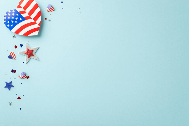 Labor Day celebration. Overhead view of patriotic ornaments: heart-shaped American flag designs, sparkling stars, confetti, set against pastel blue backdrop with a blank space for text or advertising - Fotografie, Obrázek