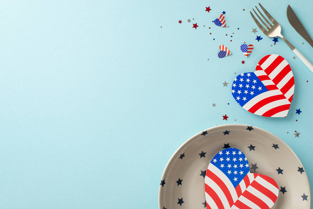 Plan for Independence Day USA with inventive table arrangement. Top view of plate, silverware, hearts featuring American flag patterns, confetti on pastel blue backdrop with space for text or advert - Foto, Imagem