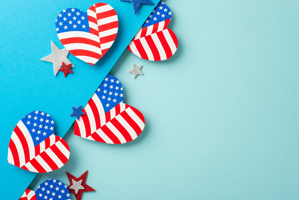 4. Juli USA fantasievolle Glückwünsche. Symbolträchtige Verzierungen von oben: Herzen mit amerikanischem Fahnenmuster, glitzernde Sterne auf zweifarbiger weicher blauer Oberfläche mit Platz für Text oder Werbung - Foto, Bild