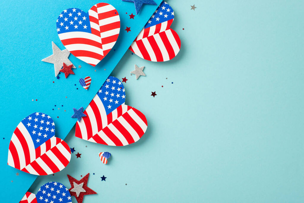 Veterans Day USA imaginative celebrations. Top view of patriotic adornments: hearts decorated with American flag pattern, glittering stars, confetti on bicolor blue surface with space for text or ad - Photo, Image