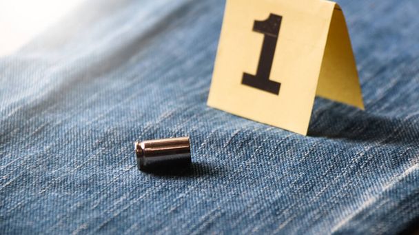 Coquilles de balles de pistolet sur un jean bleu flou et affichage numéro un en arrière-plan, concept pour la criminalité et l'enquête. foyer doux - Photo, image