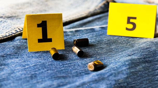 Cartuchos de bala de pistola en pantalones vaqueros azules borrosas y exhibiciones de números en segundo plano, concepto para criminal e investigación. enfoque suave - Foto, imagen