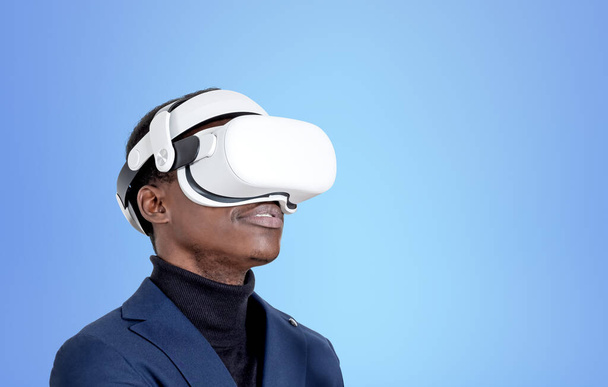 VR gözlüklü Afrikalı işadamı portresi. Fotokopi alanı boş mavi arka planda. Metaevren ve gelecek teknolojisi kavramı - Fotoğraf, Görsel