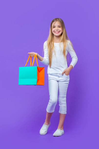 teen girl standing with shopping purchase. teen girl with shopping purchase isolated on purple. teen girl with shopping purchase in studio. teen girl with shopping purchase on background. - Fotoğraf, Görsel