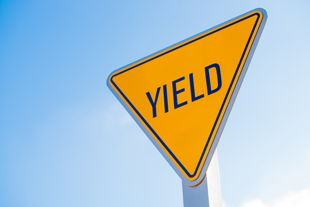 A yellow yield sign against a blue sky background - Fotoğraf, Görsel