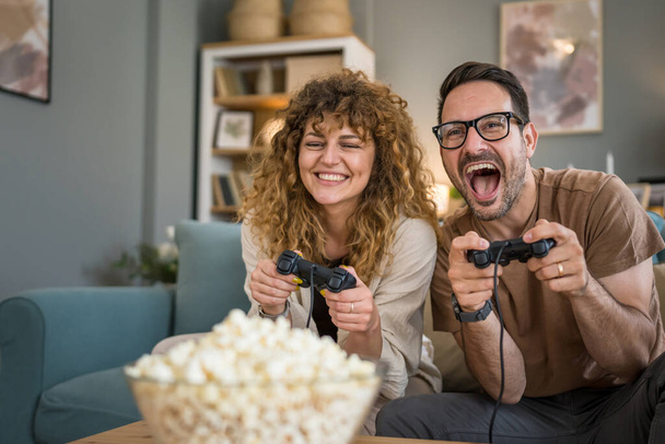 Aikuinen pari mies ja nainen valkoihoinen aviomies ja vaimo tai poikaystävä ja tyttöystävä pelata konsoli videopelejä kotona pidä joystick ohjain hauskaa vapaa-ajan iloa ja liimaus käsite kopioi tilaa - Valokuva, kuva