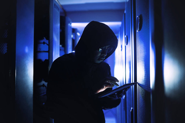 Ill crack into this system within seconds. a hacker using a digital tablet in a server room - Фото, зображення