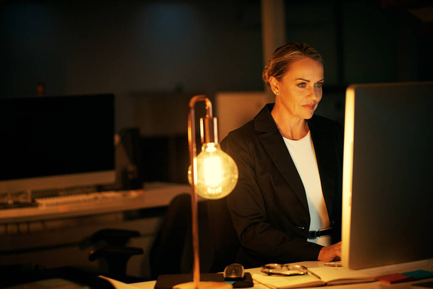 Trabajando hasta tarde en un nuevo proyecto. una mujer de negocios madura que trabaja hasta tarde en la oficina - Foto, Imagen