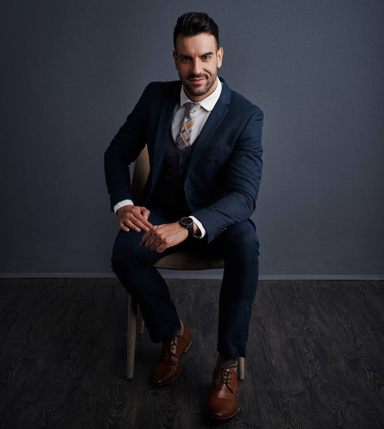 Style is part of your business brand. Studio shot of a stylish young businessman sitting on a chair against a gray background - Fotoğraf, Görsel
