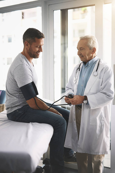 Well its definitely not your blood pressure. a senior doctor giving his male patient a thorough checkup during his consultation - Foto, Imagen