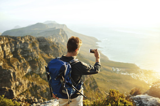 If you didnt take pictures did it really happen. a young man taking selfies while hiking up a mountain - Fotoğraf, Görsel