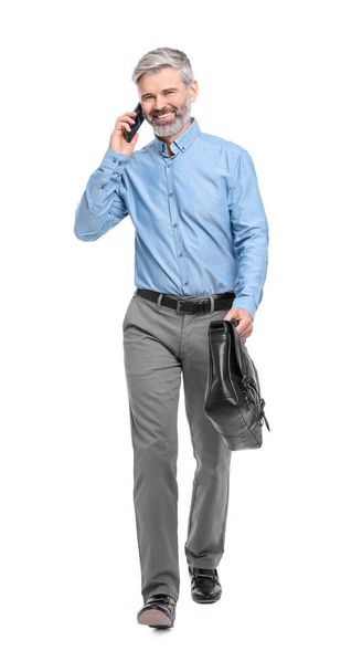 Mature businessman talking on smartphone against white background - Zdjęcie, obraz
