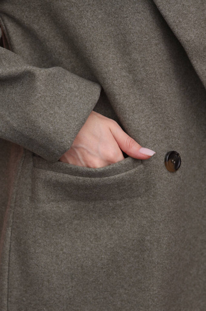 Kobieta wkłada rękę do kieszeni wełnianego płaszcza z bliska. Koncepcja mody - Zdjęcie, obraz