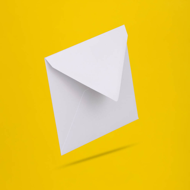 Белый пустой конверт левитации на желтом фоне с тенью - Фото, изображение