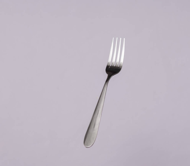 Metal fork levitating on a gray background - Foto, immagini