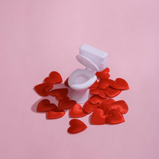 Toilet model with hearts on a pink background. Love concept, valentine's day, february 14th celebration, creative layout - Foto, Imagem
