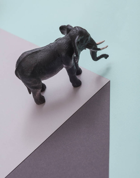 Toy elephant on paper cube. Optical illusion. Geometric composition. Minimalistic creative layout - Photo, Image