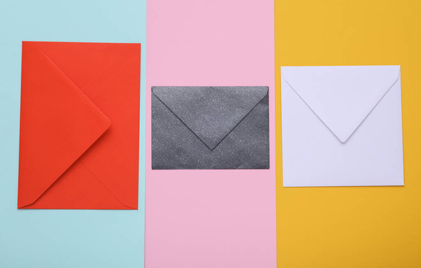 Three Envelopes of different colors and shapes on colored background - Fotografie, Obrázek
