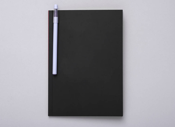 Notatnik z czarną okładką i długopisem na szarym tle - Zdjęcie, obraz