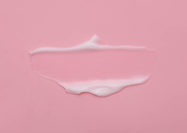 Vloeibare crème cosmetische vlek textuur op roze achtergrond met kopieerruimte - Foto, afbeelding