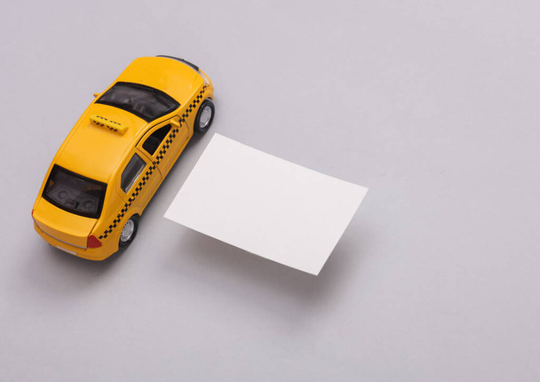 Bílá Prázdná vizitka a hračky taxi auto na šedém pozadí. Creative Mockup pro prezentace a firemní identitu. - Fotografie, Obrázek