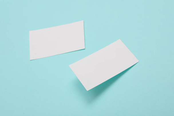 Белая пустая визитка для фирменного стиля на синем фоне. Творческий макет. - Фото, изображение