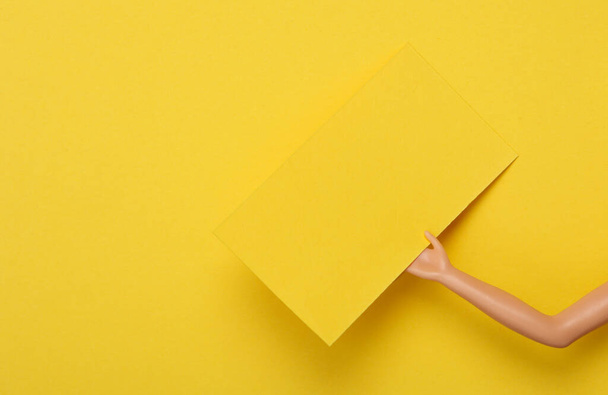 Yellow Blank business card for corporate identity in doll hand on yellow background. Creative mockup - Фото, зображення