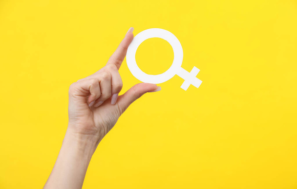 Woman's hand holding the female gender symbol of venus on a yellow background - Photo, Image