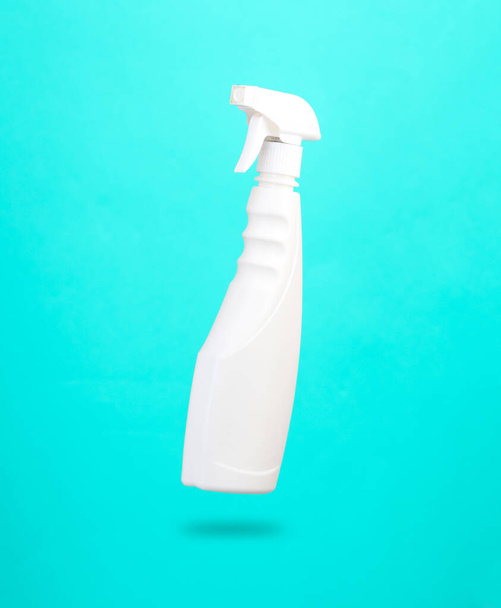 Burla de una botella blanca de aerosol limpiador de ventanas levitando sobre fondo azul con una sombra. Concepto de limpieza - Foto, imagen