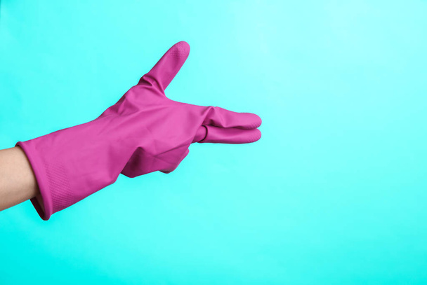 Hand in purple rubber cleaning glove on blue background. House cleaning and housekeeping concept - Φωτογραφία, εικόνα