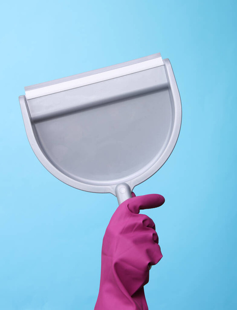 青の背景にスクープを保持紫色のゴムクリーニング手袋で手。清掃とハウスキーピングのコンセプト - 写真・画像