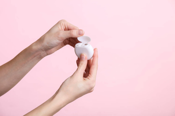 Mains féminines tenant une boîte de fil dentaire sur un fond rose. Soins dentaires - Photo, image