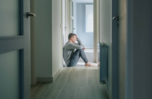 Zoufalý muž s duševními poruchami a sebevražednými myšlenkami drží hlavu s rukou na podlaze centra duševního zdraví - Fotografie, Obrázek