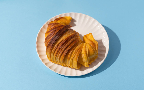 Brioche Croissant auf weißem Teller, portugiesische Hefeteigbrötchen auf blauem Hintergrund - Foto, Bild