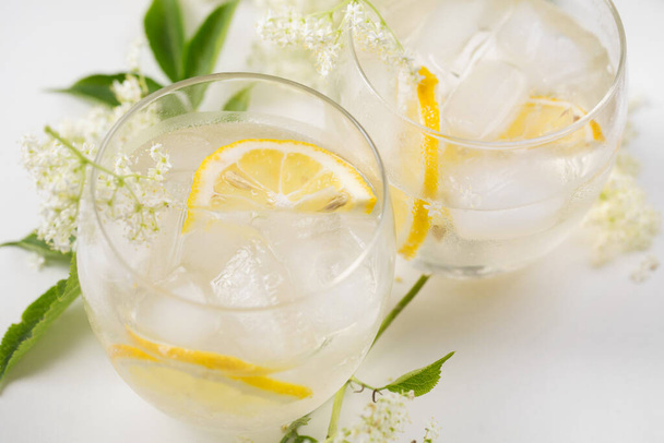 A delicious cold summer drink made of elderflowers and lemon with ice on a light background - Foto, Imagen