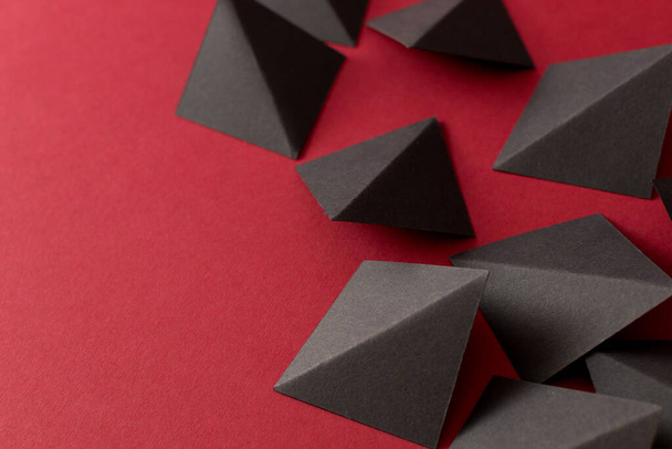 Black geometric shapes on red background, copy space - Фото, изображение