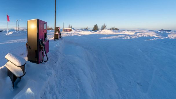 Yoğun bir kar yağışı sonrası İzlanda 'da bir benzin istasyonunda sabah güneşiyle aydınlatılan benzin ve dizel pompa. - Fotoğraf, Görsel