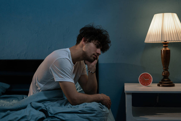 Depressziós fiatal arab férfi ül az ágyban nem tud aludni az álmatlanságtól. Depresszió és alvászavarok fogalma - Fotó, kép